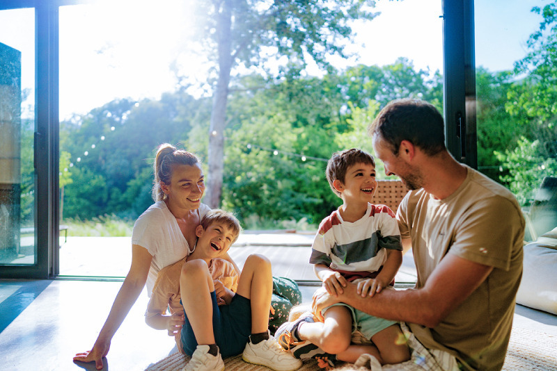 Liberty Connect photo of young family sitting on the ground in their home in front of a window, playing together