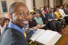 man reading bible verses to group of faithful stewards at local community event