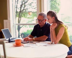 A father teaching his teenage daughter about credit card debt, financial security through a financial literacy program to ensure she has a bright financial future