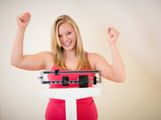 Excited woman standing on scale at home and happy with result of her slimming diet.