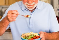 man eating bowl of fruit with natural sugars