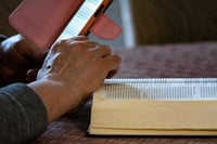 Man looking through a bible app and reading God's word for daily meditation while listening to soothing music